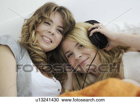 Two young women listening to music View Large Photo Image Stock Image - Two young women listening to music. Fotosearch