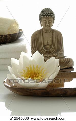 Stock Photograph - White water lily blossom, Buddha statuette and towels. Fotosearch