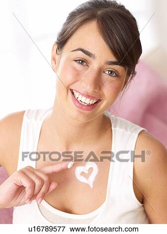 Woman applying cream in heart shape on her cleavage View Large Photo Image Stock Photo - Woman applying cream in heart shape on her cleavage. Fotosearch