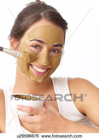 Stock Photograph - Woman applying healing earth face mask. Fotosearch