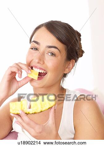 Picture - Woman eating pineapple. Fotosearch