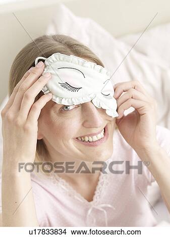Picture - Woman in bed with sleeping mask. Fotosearch