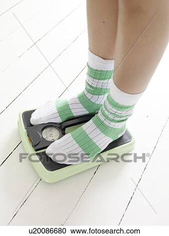 Stock Image - Woman in woolen socks standing on scales. Fotosearch