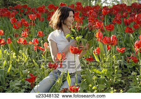 Stock Image - Woman surrounded by red tulips. Fotosearch