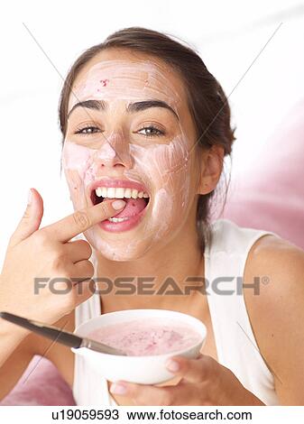 Stock Image - Woman tasting fruit face mask. Fotosearch