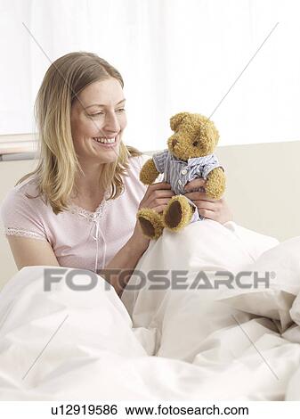 Stock Photograph - Woman with teddy in bed. Fotosearch