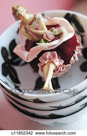 Stock Image - Womans figurine sitting on stack of bowls. Fotosearch