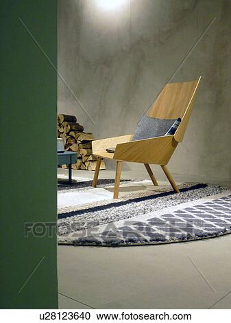 Stock Image - Wooden chair and firewood in room with concrete wall. Fotosearch