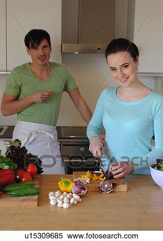 Stock Photography - Young couple in kitchen preparing salad. Fotosearch