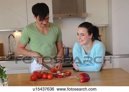 Young couple in kitchen slicing vegetables View Large Photo Image Stock Photograph - Young couple in kitchen slicing vegetables. Fotosearch