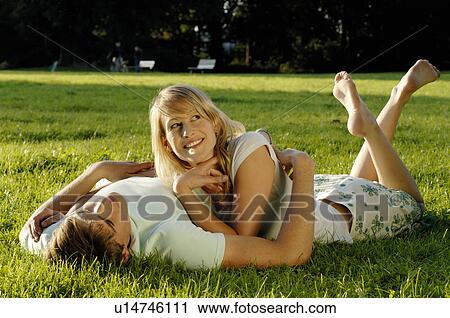 Stock Image - Young couple lying in meadow. Fotosearch