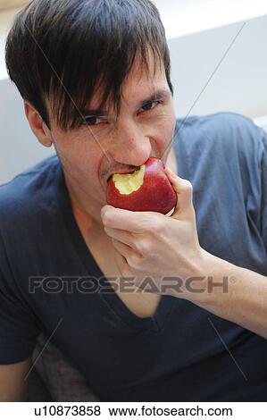 Young man eating an apple View Large Photo Image Stock Photo - Young man eating an apple. Fotosearch