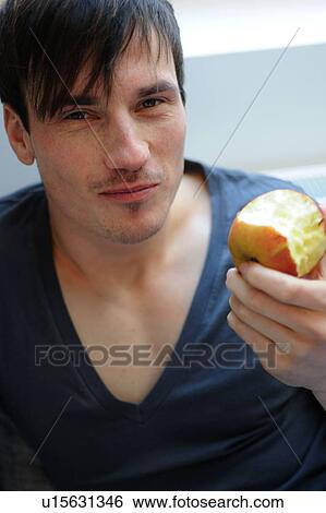 Young man eating an apple View Large Photo Image Stock Photograph - Young man eating an apple. Fotosearch