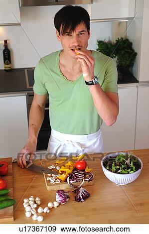 Young man in kitchen preparing salad View Large Photo Image Stock Photo - Young man in kitchen preparing salad. Fotosearch