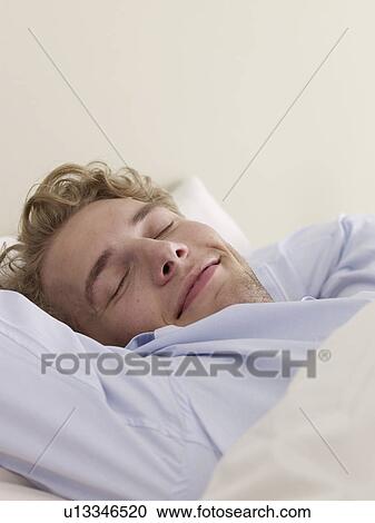 Stock Image - Young man lying in bed. Fotosearch