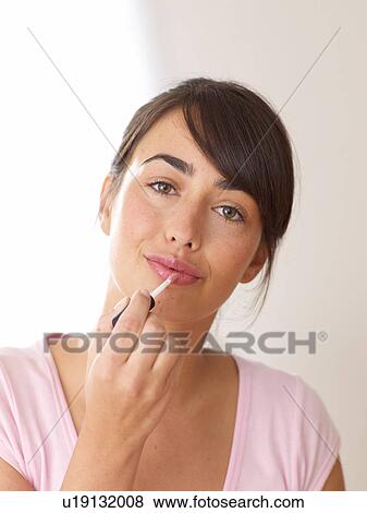 Stock Photo - Young woman applying lipstick. Fotosearch