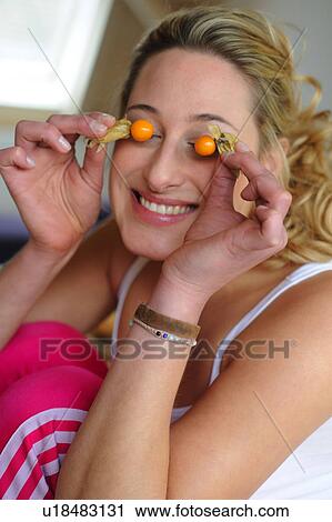 Stock Image - Young woman covering her eyes with fruit. Fotosearch