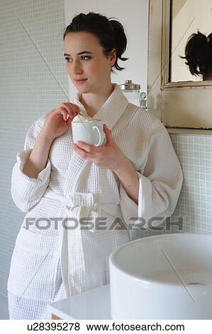 Stock Photo - Young woman drinking coffee in bathroom. Fotosearch
