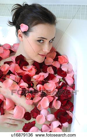Stock Photograph - Young woman enjoying bath with rose petals. Fotosearch