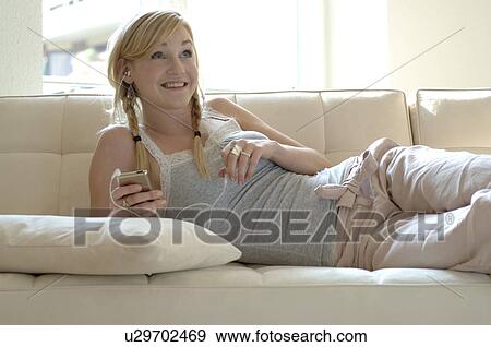 Young woman listening to music on couch View Large Photo Image Stock Photo - Young woman listening to music on couch. Fotosearch
