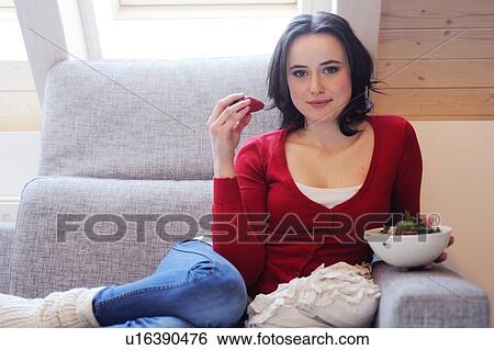 Young woman on couch eating strawberries View Large Photo Image Stock Photograph - Young woman on couch eating strawberries. Fotosearch