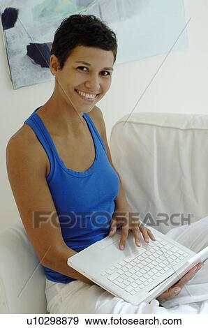 Young woman using laptop on couch View Large Photo Image Stock Photo - Young woman using laptop on couch. Fotosearch
