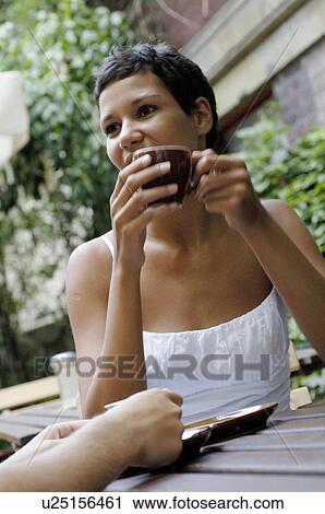 Stock Image - Young woman with cup of coffee outdoors. Fotosearch