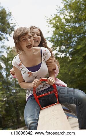 Stock Image - 2 girls having fun together in a park. Fotosearch