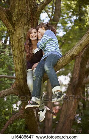 Stock Photo - 2 girls having fun together in a tree. Fotosearch