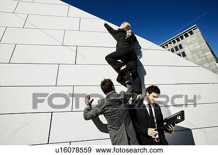 Stock Photo - 2 men helping woman over wall. Fotosearch