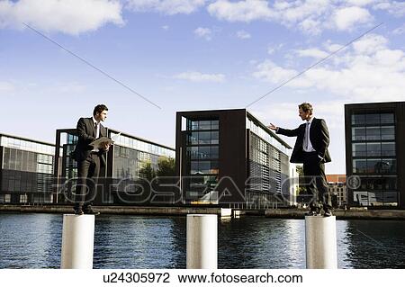 Stock Image - 2 men on poles. Fotosearch