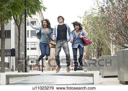 Stock Photo - 3 young people jumping in street. Fotosearch