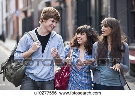 Stock Photograph - 3 young people walking in street. Fotosearch