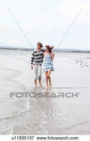 Stock Photo - A couple take a romantic beach stroll. Fotosearch