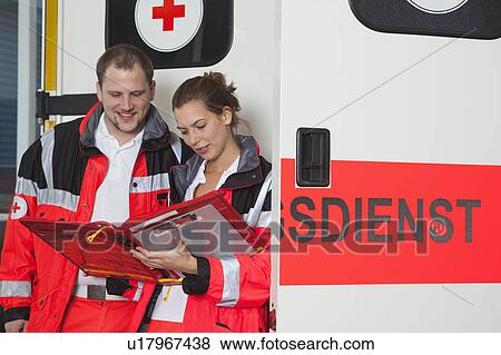 Stock Photo - Ambulance team examining file at coach. Fotosearch