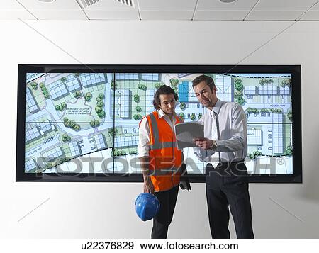 Stock Photo - Architects in front of plans on screen. Fotosearch
