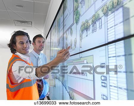 Stock Image - Architects work with plans on screen. Fotosearch