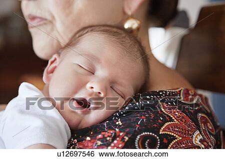 Baby asleep on grandmothers shoulder View Large Photo Image Stock Photograph - Baby asleep on grandmothers shoulder. Fotosearch