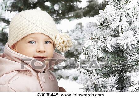 Stock Photography - Baby girl beside snowy trees. Fotosearch