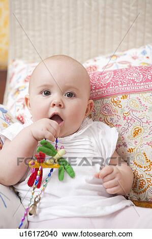 Stock Image - Baby sitting on bed. Fotosearch