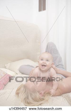 Baby with Mother laying in bed View Large Photo Image Stock Photo - Baby with Mother laying in bed. Fotosearch