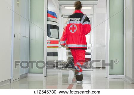 Stock Image - Back of paramedic rushing at hall. Fotosearch