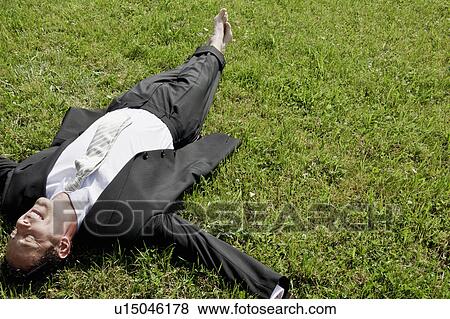 Stock Photo - Barefoot businessman lying on grass. Fotosearch