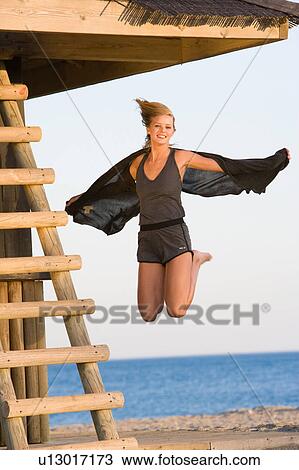 Stock Image - Beautiful girl jumping beach. Fotosearch