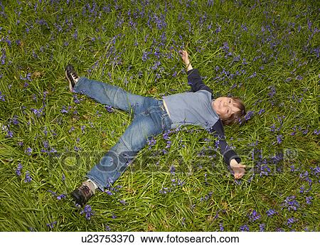 Stock Image - Boy (6-8) lying in field of bluebells. Fotosearch