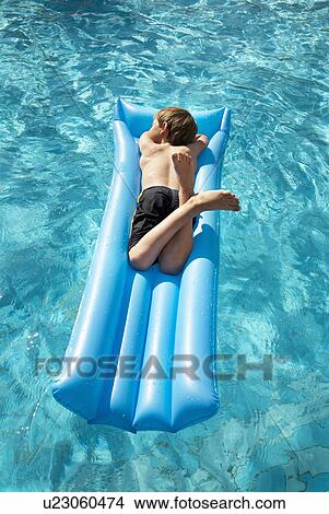 Picture - Boy (7-9) lying on lilo in pool. Fotosearch