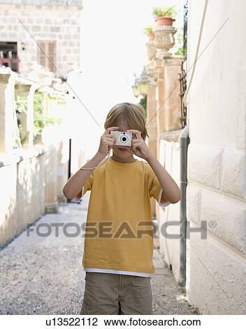 Stock Image - Boy (8-10) taking photograph. Fotosearch