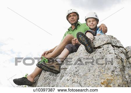 Stock Photo - Boy and man sitting on a rock. Fotosearch