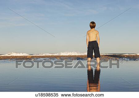 Boy and reflection standing on the beach View Large Photo Image Stock Photography - Boy and reflection standing on the beach. Fotosearch