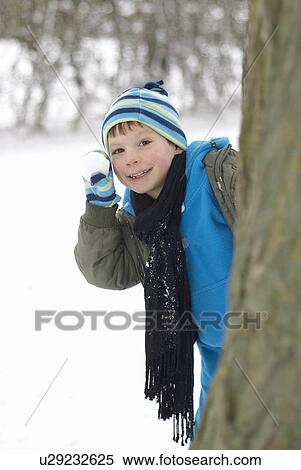 Boy hiding behind tree with snowball View Large Photo Image Stock Photography - Boy hiding behind tree with snowball. Fotosearch